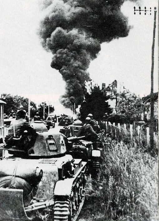 Soldiers on tanks advance down a rural road as thick smoke rises from burning buildings in the background.