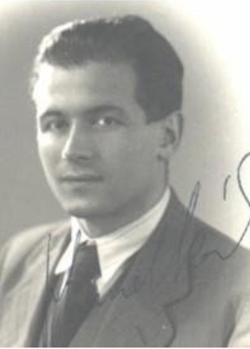Black-and-white portrait of a young man in a suit and tie, facing the camera, with short dark hair; an autograph is visible across the photo.