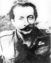 Black and white photo of a man in military uniform with a moustache, smiling, and looking at the camera.