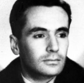 Black and white portrait of a man with dark hair, wearing a collared shirt and jacket, looking slightly to his left.