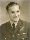 A young man in military uniform poses for a formal studio portrait, smiling slightly. He wears a jacket with medals, a tie, and has neatly combed hair.
