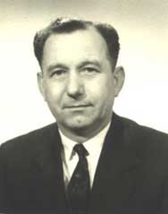Black and white portrait of a middle-aged man in a suit and tie, facing forwards against a plain background.