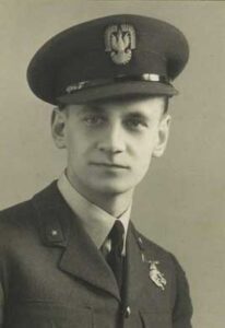 Young man in a military uniform and peaked cap with an eagle emblem, facing the camera and posing for a formal portrait.