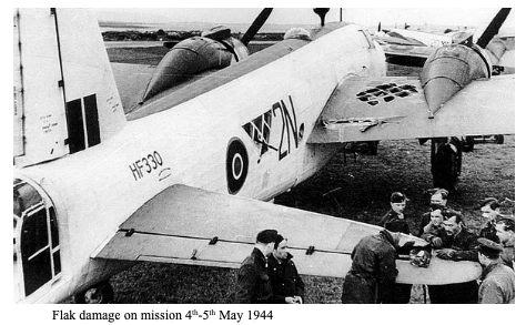 A Second World War RAF bomber with visible flak damage is inspected by aircrew and ground staff on an airfield, May 1944.