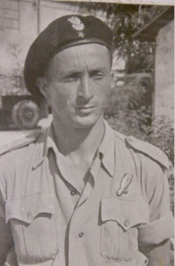 Black and white photo of a man in military uniform and beret, standing outdoors with a neutral expression.