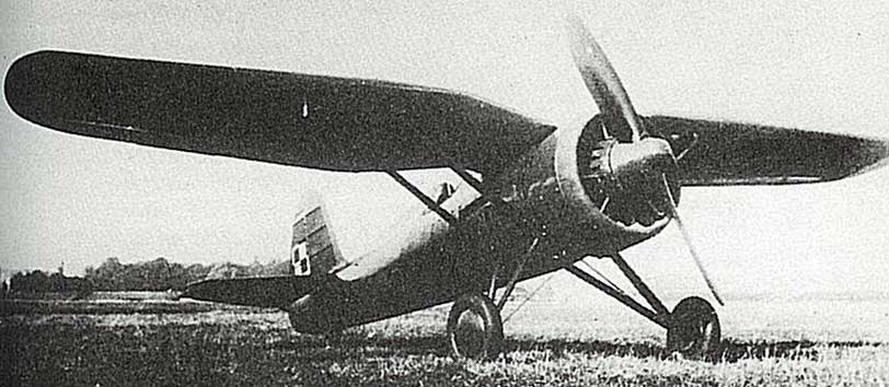 Black and white photo of a vintage single-engined monoplane with fixed undercarriage and a radial engine, parked on a grassy field.