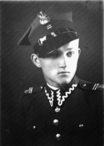 Black-and-white portrait of a young man in a military uniform and cap, looking slightly to the side, with visible insignia and decorative buttons.