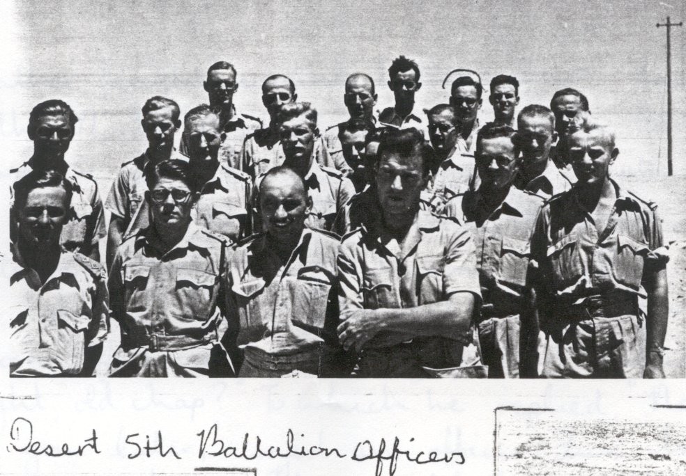 Black-and-white photo of a group of men in military uniforms standing outdoors, labelled "Desert 5th Battalion Officers" at the bottom.