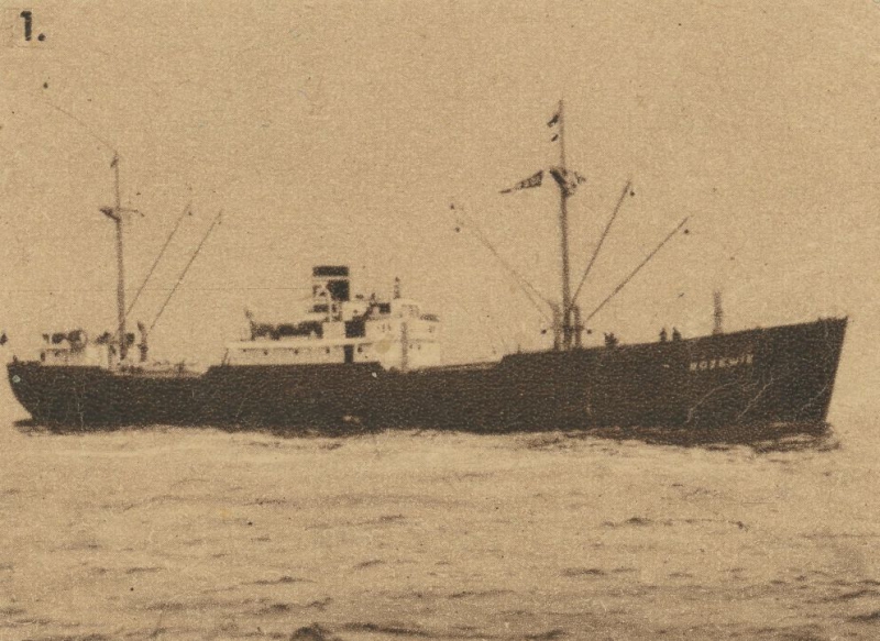 Black-and-white photo of a cargo ship sailing on the sea, with visible masts, cranes, and a funnel.
