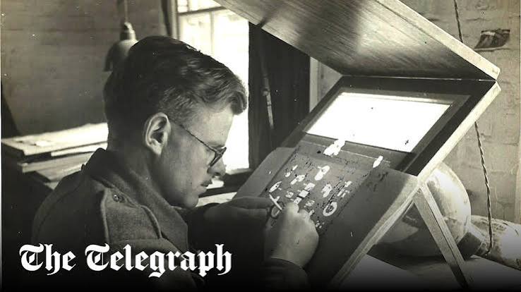 A man in spectacles works intently at a desk with a slanted lightbox, examining or repairing small objects. The Telegraph logo is visible in the lower left corner.
